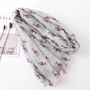 Detail of light gray scarf with purple deer prints and fringe, beside a magazine