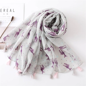 Detail of deer print scarf with fringe edges next to minimalist lifestyle magazine