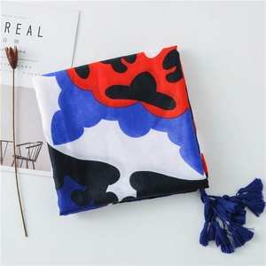 Detail of blue tassel on abstract floral scarf with magazine and dried flower backdrop