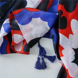Detail of artistic blue and red floral scarf featuring dense navy tassel pendants