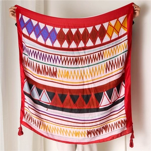 Detailed view of bohemian red beach shawl with vibrant geometric patterns and fringe tassels
