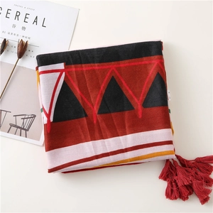 Close-up of geometric pattern scarf with thick red fringe tassels and soft fabric texture