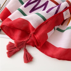 Macro shot of red tassels and colorful wave pattern on polyester beach shawl