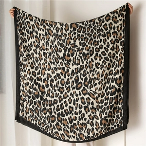 Detailed view of leopard print scarf with wide black borders held up by a person