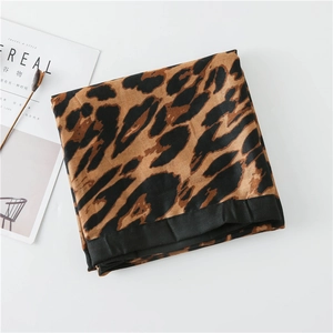 Detail of leopard print cotton-linen shawl with black stitched edges on white background