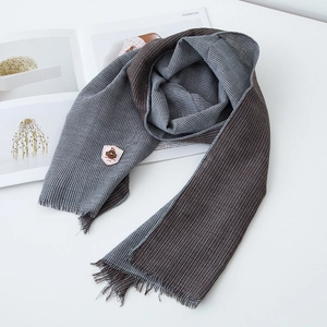 Close-up of houndstooth cotton scarf with fringed edges and embroidered badge detail
