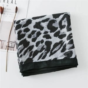 Detailed view of leopard print cotton linen scarf with black border on a minimalist background