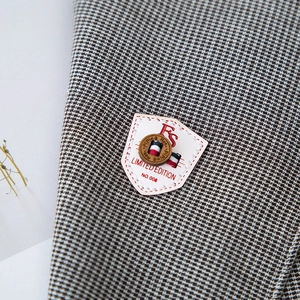 Macro view of houndstooth scarf texture with leather patch and wooden button detail