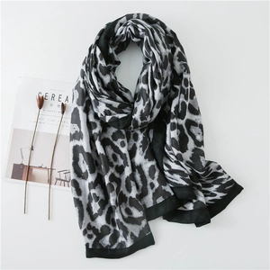 Chic leopard print cotton linen scarf with black border on a minimalist white backdrop