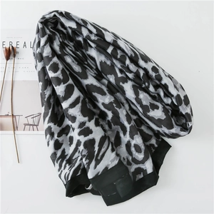 Detail of grey leopard print scarf with wide black border laying on a white surface