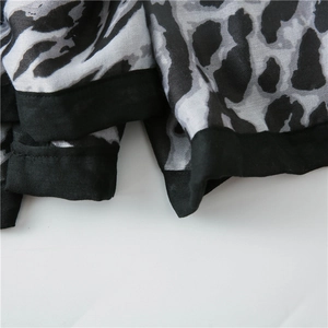 Macro detail of leopard print cotton linen scarf with black border and neat stitching