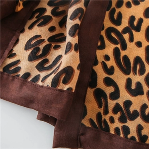 Close-up of leopard print cotton linen scarf with thick dark brown hem and woven texture
