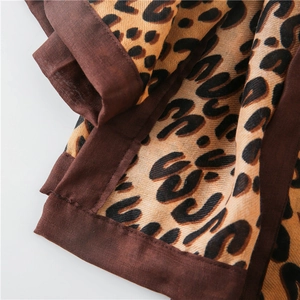 Detailed close-up of leopard print cotton linen scarf with thick stitched edge and soft texture