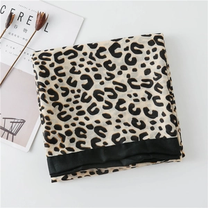 Detail shot of folded linen leopard print scarf with black borders and magazine decor
