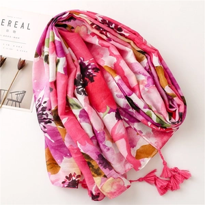 Detail of floral print linen-feel shawl with pink tassels on a minimalist background