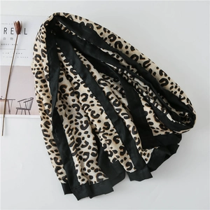 Detail of soft leopard print scarf with wide black hem and minimalist magazine background