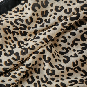 Detail view of cotton linen shawl showing leopard print pattern and black hemmed edge