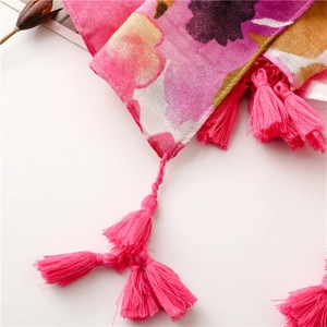 Macro detail of floral print scarf with bright pink tassels and woven fabric texture
