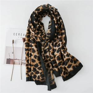 Flat lay detail of leopard print scarf with black borders next to minimalist decor