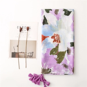 Detail of artistic floral print scarf with soft purple tassels on minimalist background