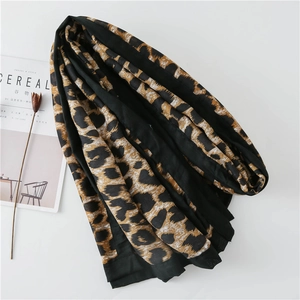 Detail of soft leopard print shawl with wide black hem and lifestyle decor
