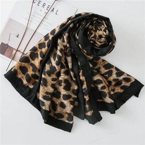 Detailed flat lay of leopard print scarf with black borders next to a magazine