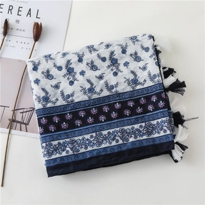 Close-up of a blue floral linen scarf with ethnic patterns and fringe detail