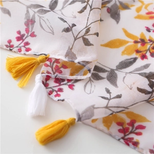 Close-up of lightweight linen scarf showing red floral patterns and yellow fringe details