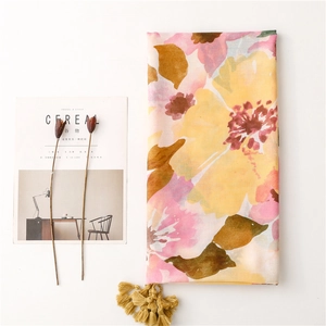 Detail of floral linen scarf featuring soft yellow and pink print with yellow tassels