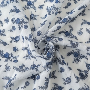 Close-up of blue floral patterns on wrinkled white cotton linen shawl fabric