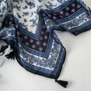 Detailed macro view of cotton-linen scarf with floral patterns and dark blue fringe trim