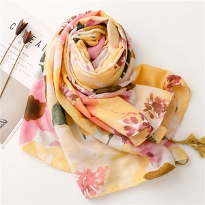 Detail of yellow and pink floral scarf with elegant tassels and soft linen texture