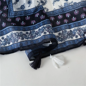 Detail of floral ethnic scarf with blue white patterns and bicolor fringe tassels