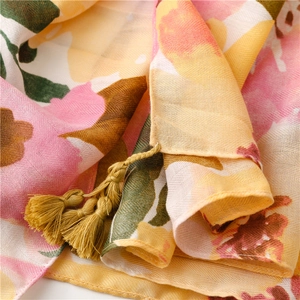 Detail of floral linen scarf showing soft fabric texture and yellow tassel fringe