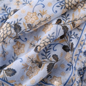 Detail of light blue cotton linen scarf featuring vintage floral print and fabric texture