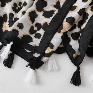 Close-up of leopard print scarf fabric texture with detailed black and white tassels
