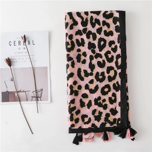 Detail of pink leopard print scarf with fringe tassels on minimalist white background