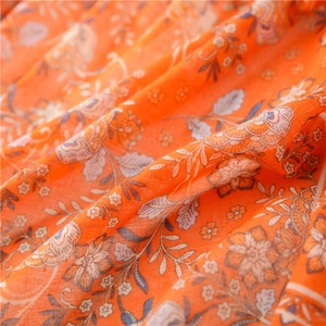 Detailed macro shot of vintage floral pattern on soft orange cotton linen shawl fabric