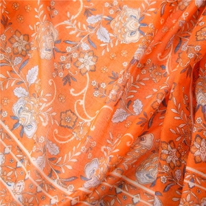 Detailed close-up of orange bohemian paisley floral print on soft linen scarf fabric