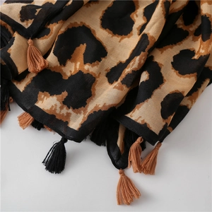 Detailed view of leopard print cotton linen scarf featuring dark brown tassel fringe trim