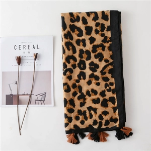 Detail of leopard print scarf with tassels alongside magazine and dried flowers