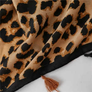 Detail view of leopard print scarf featuring soft texture and decorative brown fringe tassels