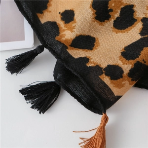 Macro view of leopard print scarf fabric texture with handcrafted black fringe tassels