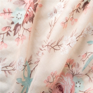 Detailed close-up of floral print cotton linen fabric with soft pink and green patterns
