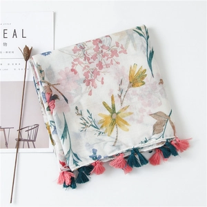 Detail of floral linen shawl with vibrant pink and teal tassels on white background