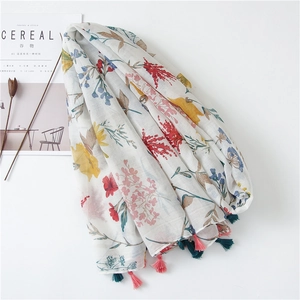 Detailed macro of white cotton linen scarf with floral print and dual-tone tassels