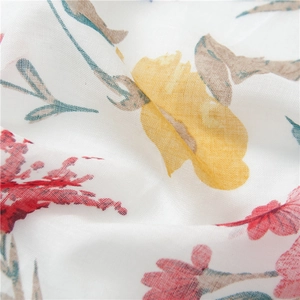Close-up of white linen fabric with vibrant red and yellow floral print and tassel details