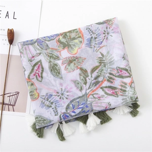 Close-up of lightweight cotton linen scarf featuring green leaf patterns and fringe edges