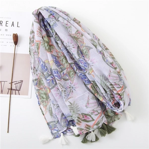Close-up of lightweight cotton-linen scarf with green leaf print and tassel fringe details
