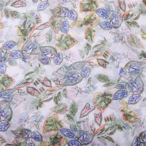 Detailed macro view of linen scarf fabric with vibrant green leaf prints and soft textures